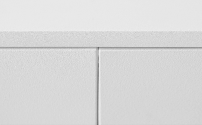 A close-up detail of the minimal spacing between the doors of a white sideboard.